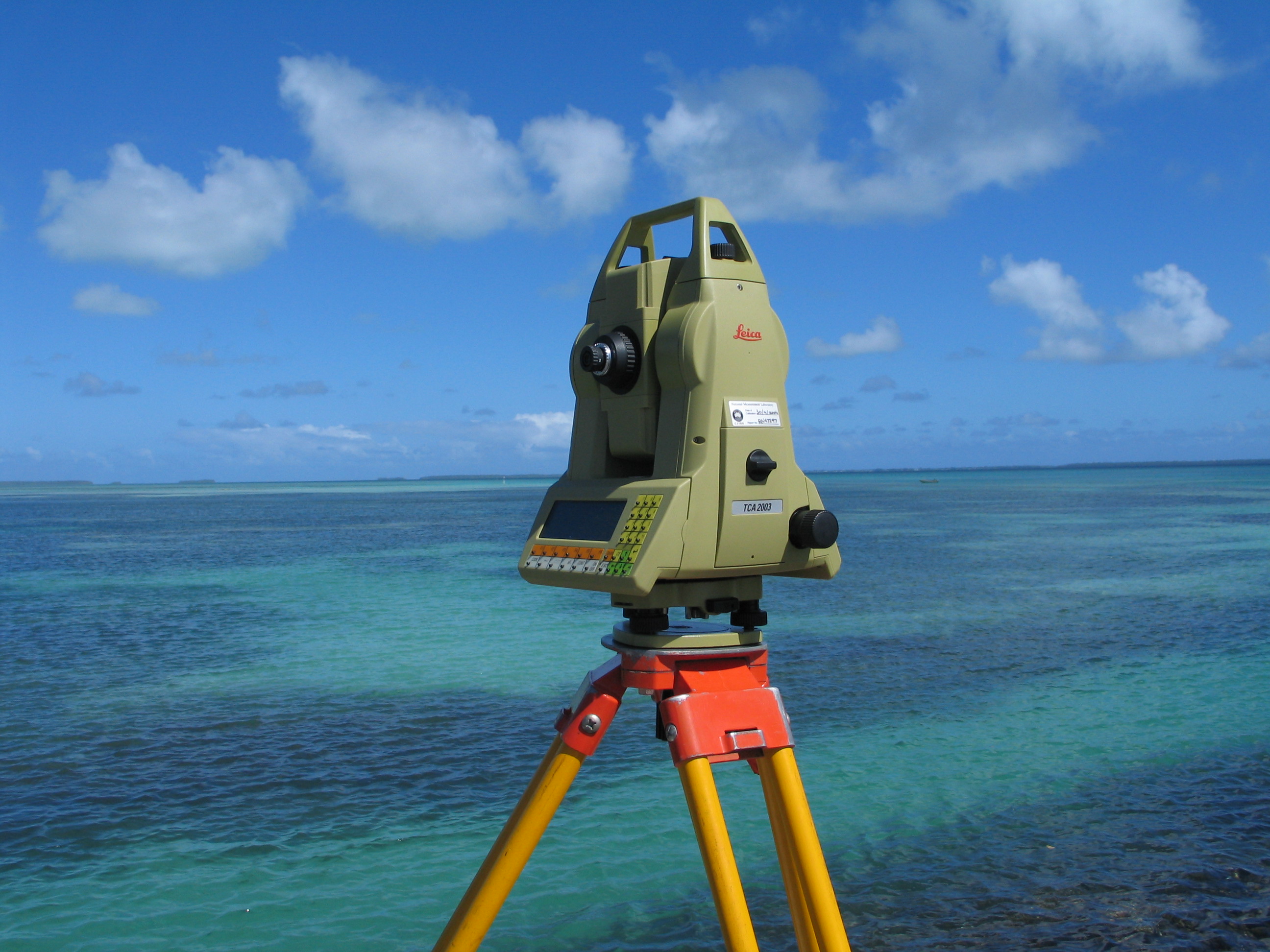 Picture of a modern day total station Theodolite machine, lookng out over an ocean view.